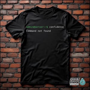Könnte beinhalten: Schwarzes T-Shirt mit dem Text "admin@server:~$ confidence Command not found" in Grün und Weiß. Das T-Shirt hat einen Rundhalsausschnitt und kurze Ärmel. Das Markenlogo "SHOCK WAVE INK & THREAD" befindet sich unten rechts.