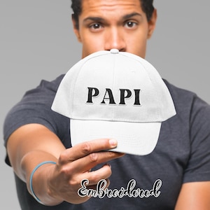 May include: White baseball cap with black embroidered text that reads "PAPI".