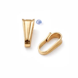 May include: Two gold-coloured jewellery findings on a white background. One is a pendant bail with a V-shaped design, and the other is an oval-shaped clasp. A small, light blue gemstone is also present.