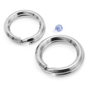 Op de afbeelding: Twee zilverkleurige split sleutelringen met een kleine, lichtblauwe kraal. De sleutelringen zijn cirkelvormig met een split opening voor het toevoegen van sleutels. De kraal is klein, rond en doorschijnend blauw.