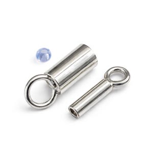 May include: Two silver-coloured jewellery clasps with eyelet loops and a small, light blue bead. The clasps are cylindrical with a polished finish. One clasp is open, and the other is closed. The bead is round and translucent.