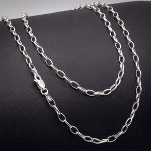 May include: A silver chain necklace featuring oval links and a lobster clasp. The necklace is presented on a black surface, highlighting its shine. This chain is a classic piece of jewellery.