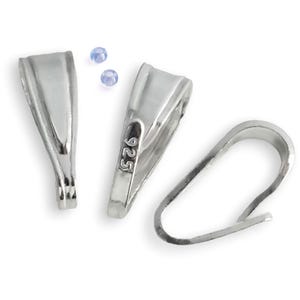 May include: A collection of silver-colored jewelry findings, including two pendant bails and a clasp. The pendant bails have a curved design and a small loop for attaching to a chain or cord. The clasp is a simple, curved hook. Two small, light blue beads are also present.