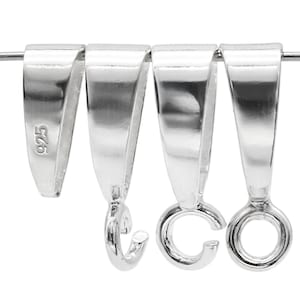 Puede incluir: Primer plano de cuatro colgantes plateados. Uno de ellos está estampado con "925". Los colgantes tienen un diseño curvo con un lazo en la parte inferior para sujetarlos a las joyas. Los colgantes están sobre un alambre fino.