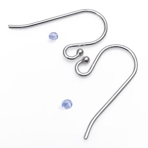 May include: Two silver-toned metal earring hooks with a curved wire design and a small ball accent at the loop end. Two tiny, translucent, light blue spherical beads are positioned separately near the metal earring findings.
