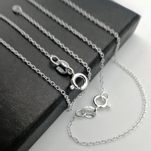 May include: A silver chain necklace with a lobster clasp fastening. The chain is made of small, linked ovals.