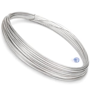 Può includere: Un fascio di filo metallico argentato, avvolto strettamente, con una piccola perla azzurra vicina. Il filo sembra essere di metallo lucido, forse per la creazione di gioielli o lavori artigianali.