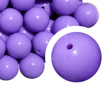 May include: A close-up of a pile of large, round, purple beads. The beads are smooth and shiny, with a small hole in the center of each bead.