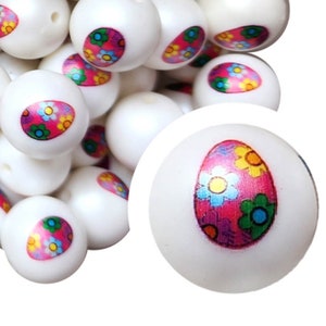 May include: White round beads with a colorful floral design. The beads have a smooth surface and a small hole for stringing. The floral design features pink, yellow, blue, and green flowers.