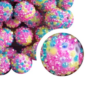 May include: A collection of colorful, rhinestone-covered beads. The beads are primarily pink, with accents of yellow, blue, and iridescent rhinestones. Each bead has a hole for stringing. These beads are ideal for jewelry making and craft projects.