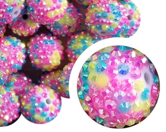 Op de afbeelding: Een verzameling kleurrijke kralen bedekt met strass. De kralen zijn voornamelijk roze, met gele, blauwe en iriserende strass accenten. Elke kraal heeft een gat om te rijgen. Ideaal voor het maken van sieraden en knutselprojecten.