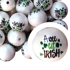 Könnte beinhalten: Weiße Holzperlen mit grünen Kleeblatt-Designs und dem aufgedruckten Text "A wee bit Irish".