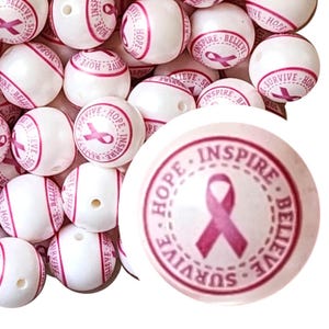 May include: White beads with pink text and a pink ribbon design. The text includes the words "Hope, Inspire, Believe, Survive". These beads are suitable for jewelry making and craft projects.