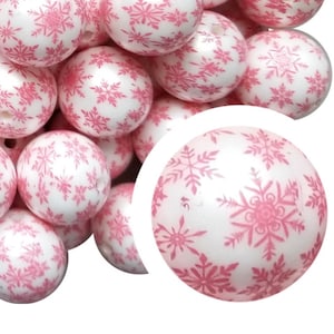 May include: A collection of white, round beads with a pink snowflake pattern. The beads are clustered together, with a close-up view of one bead showing the intricate design. These beads are suitable for jewelry making and craft projects.