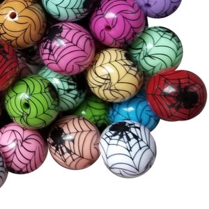 Puede incluir: Una colección de cuentas redondas y coloridas con temática de Halloween. Cada cuenta presenta un diseño de telaraña y una araña negra. Las cuentas son de varios colores, incluyendo rosa, verde, amarillo y rojo.