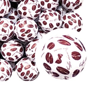 May include: A close-up of a pile of white wooden beads with a brown coffee bean pattern and the text "Coffee Beans" printed on them.