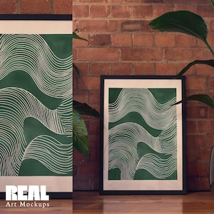 May include: Two framed prints with a green background and white abstract line designs. The frames are black and the prints are hanging on a brick wall.