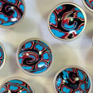 May include: Ten small, round, silver-rimmed bowls with a swirling pattern of black, blue, and red paint.