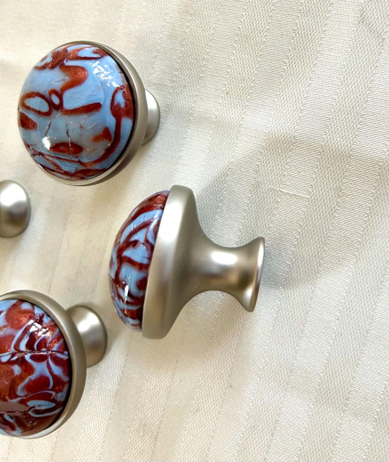 May include: Four cabinet knobs with a silver base and a blue and red marbled design.