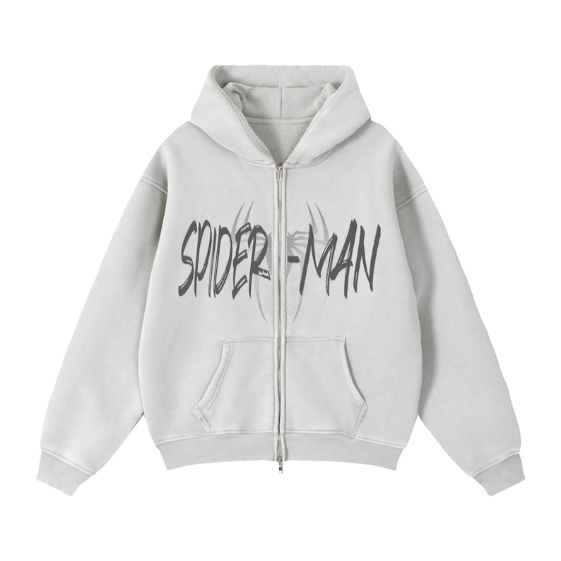 Puede incluir: Sudadera con capucha gris claro con cremallera, bolsillo delantero y capucha. La sudadera presenta las palabras "SPIDER-MAN" en una fuente negra desgastada en el pecho. El dise&ntilde;o incluye una telara&ntilde;a.