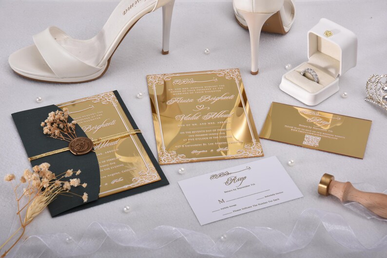 May include: Gold and black wedding invitations with a gold mirror finish. The invitations feature a white floral design and the text "Alice & Bayleigh" and "Wedding Album".