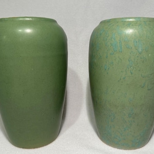 May include: Two green ceramic vases, one with a smooth finish and the other with a mottled, textured finish.
