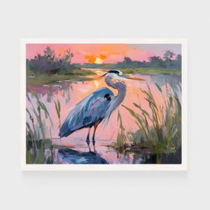 May include: An oil painting of a Great Blue Heron standing in water, with a sunset in the background. The heron is depicted in shades of blue and gray, with an orange beak. Tall green reeds surround the bird, and the sky is a mix of pink, orange, and yellow.