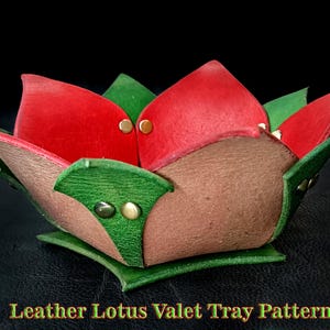 May include: A handcrafted leather valet tray in the shape of a lotus flower. The tray features red and green petals with brass rivets. The base is a square shape with green leather. The text "Leather Lotus Valet Tray Pattern" is visible.