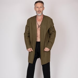 May include: An olive green long-sleeve jacket and black trousers. The jacket is open at the front and reaches the knees. The trousers are loose-fitting. A black beaded necklace with a cross pendant is worn.