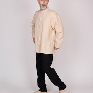 May include: A light beige long-sleeved shirt with a mandarin collar and black pants. The shirt is loose-fitting and the pants are straight-legged. The outfit is simple and comfortable, suitable for casual wear.