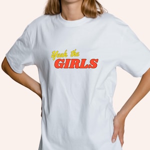 May include: White t-shirt with the text "Yeah the GIRLS" in red and yellow lettering.