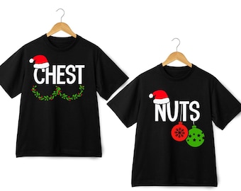 May include: Two black t-shirts with a Christmas theme. One shirt says "CHEST" with a Santa hat and holly. The other shirt says "NUTS" with a Santa hat and two Christmas baubles.