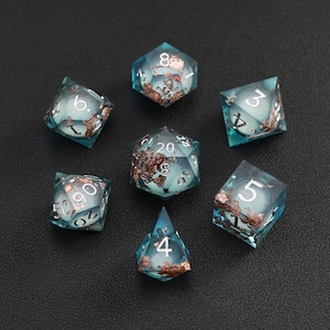 May include: Set of seven polyhedral dice with a teal and copper color scheme. The dice are transparent, with copper-colored inclusions and white numbers. The dice are arranged on a dark surface.