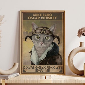 May include: A vintage-style poster featuring a gray cat wearing a brown leather aviator jacket and goggles. The text on the poster reads "Mike Echo Oscar Whiskey How Do You Copy? Over".