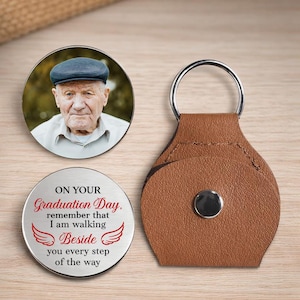 May include: A personalized graduation gift set featuring a round photo pendant, a round engraved keepsake with the text "On Your Graduation Day," and a brown leather keychain. The photo pendant displays a portrait of an elderly man. The keychain has a silver ring.
