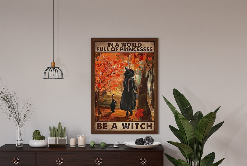May include: A vintage-style poster with a witch and her black cat walking through a forest of autumn leaves. The text reads "In a world full of princesses, be a witch."