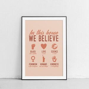 Pu&ograve; includere: Un poster rosa e marrone con il testo "In questa casa crediamo:" e un elenco di valori che includono "Le vite nere contano", "L'amore &egrave; amore", "La scienza &egrave; reale", "Il femminismo &egrave; per tutti", "Gli umani non sono illegali" e "La gentilezza &egrave; tutto".