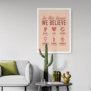Pu&ograve; includere: Una stampa incorniciata con uno sfondo color pesca e una cornice bianca. La stampa dice "In questa casa crediamo" e elenca diversi valori, tra cui "Black lives matter", "L'amore &egrave; amore", "La scienza &egrave; reale", "Il femminismo &egrave; per tutti", "Gli umani non sono illegali" e "La gentilezza &egrave; tutto".