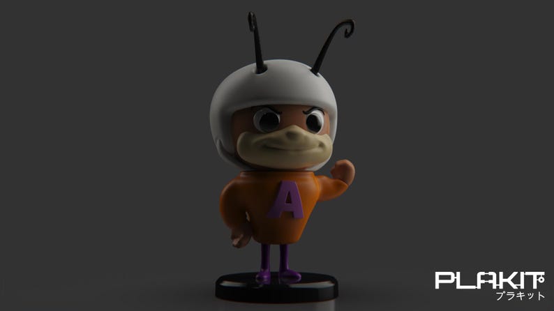 Puede incluir: Una figurita de personaje de dibujos animados con un casco blanco, un cuerpo naranja y botas moradas. El personaje tiene una nariz grande y marr&oacute;n y una letra "A" morada en el pecho. La figurita est&aacute; de pie sobre una base negra.