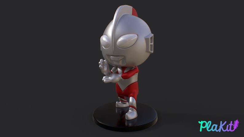May include: A silver and red figurine of a character with a large head, oval eyes, and a smiling expression. The figure is posed with one hand raised. It stands on a black circular base. The figurine is a collectible item.