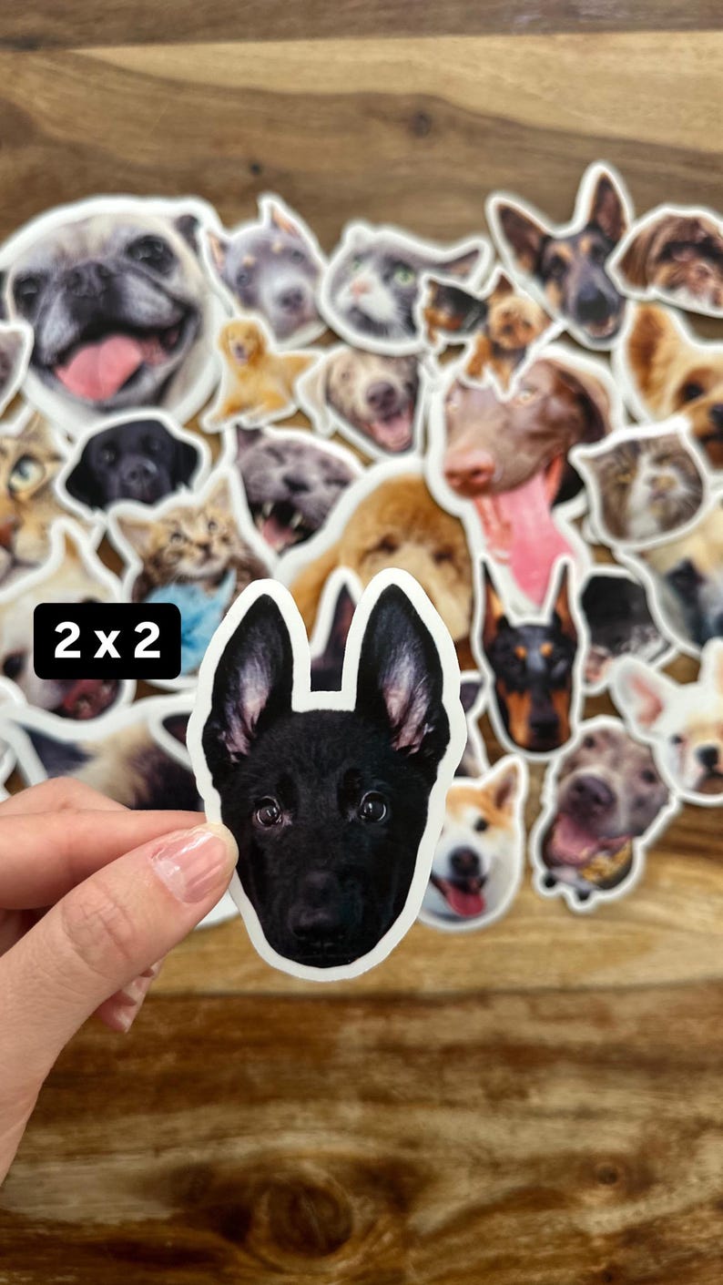 May include: A selection of dog stickers showcasing different breeds, with a black German Shepherd sticker prominent in the front. The stickers are in various colours and poses. The text "2 x 2" is in the upper left corner.