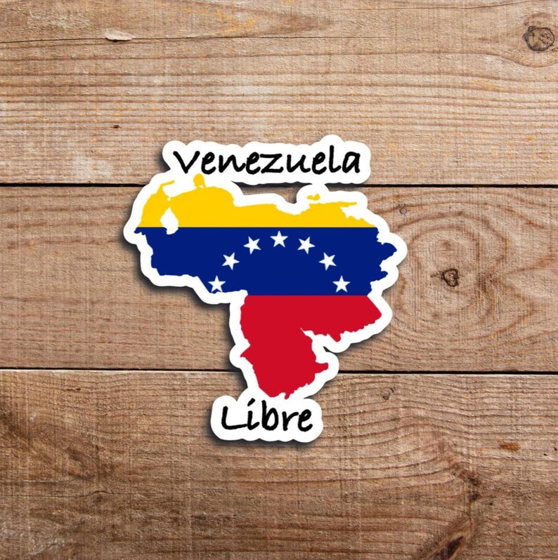 May include: A sticker depicting the map of Venezuela, coloured with the national flag's colours: yellow, blue, and red. The word "Venezuela" is above the map, and "Libre" is below. The sticker is placed on a wooden background.