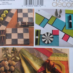 May include: A Vogue Decor pattern envelope showcasing home decor designs. The projects include a checkerboard tray, geometric placemats, and table runners with striped patterns. The envelope is white and has the pattern number V7955.