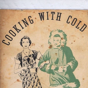 May include: A vintage cookbook cover with the title "Cooking with Cold." The cover shows illustrations of two figures, one in an apron and the other in a parka. The text below reads "Practical recipes to help you get greater use and pleasure from your new Norge Rollator Refrigerator."