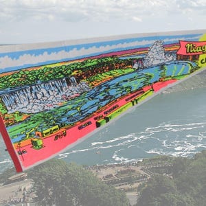 May include: A colourful pennant flag depicting Niagara Falls, with the text "Niagara Falls CANADA" in red and yellow. The flag has a red border and a triangular shape, with a scenic view of the falls.