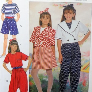 May include: A sewing pattern for girls' clothing. The pattern includes three different outfits: a red and white polka dot top with a red and white striped skirt, a white sailor top with black and white polka dot pants, and a red jumpsuit with a red and white striped belt.