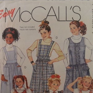 Peut inclure: Un patron de couture vintage McCall's avec des illustrations de filles portant des robes à bretelles. Le patron comprend des modèles de robes à carreaux, à pois et à rayures. Taille 10. Le texte indique 'Easy McCall's'.