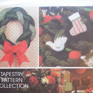 May include: A vintage tapestry pattern collection cover featuring Christmas-themed designs. The cover includes images of a green wreath with a red bow, a decorated Christmas tree, and placemats with matching napkins. The text reads "Designed exclusively for Avon by McCall Patterns."