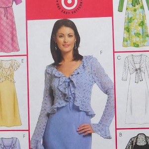 May include: A sewing pattern featuring six dress designs. The dresses include various styles, such as a pink plaid dress with a matching bolero, a yellow dress with ruffled sleeves, and a blue dress with a lace jacket. The text "GREAT LOOKS" and "ONE EASY PATTERN" is visible.
