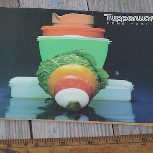 Könnte beinhalten: Eine Vintage-Broschüre von Tupperware Home Parties mit einem Stapel grüner, orangefarbener und weißer Plastikschalen mit einem grünen Blattgemüse und einer mehrfarbigen Frucht darin.